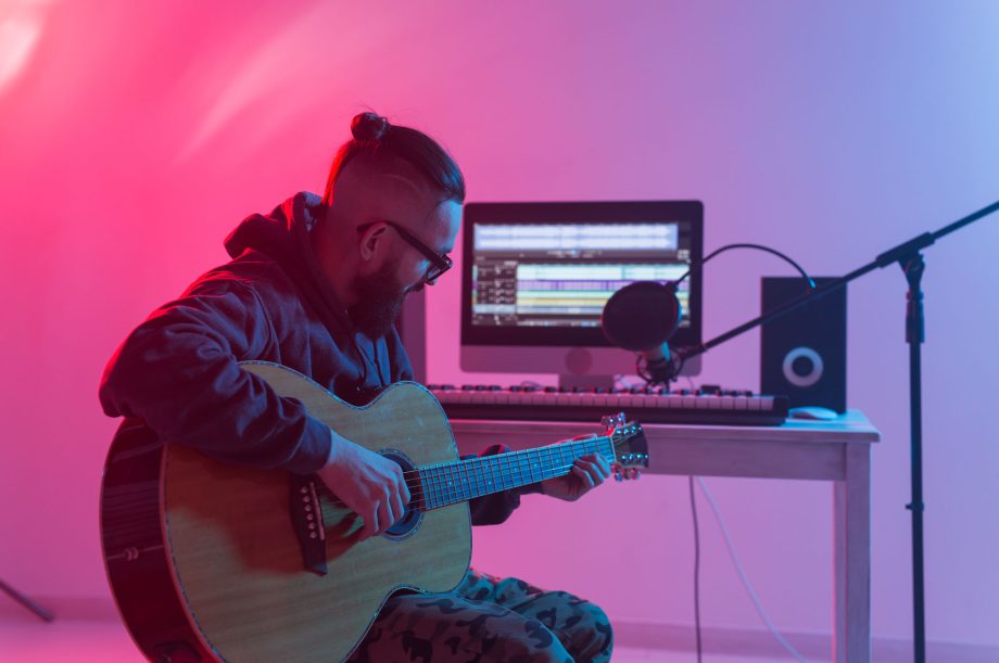 Create music and a recording studio concept - Bearded man guitarist recording electric guitar track in home studio.